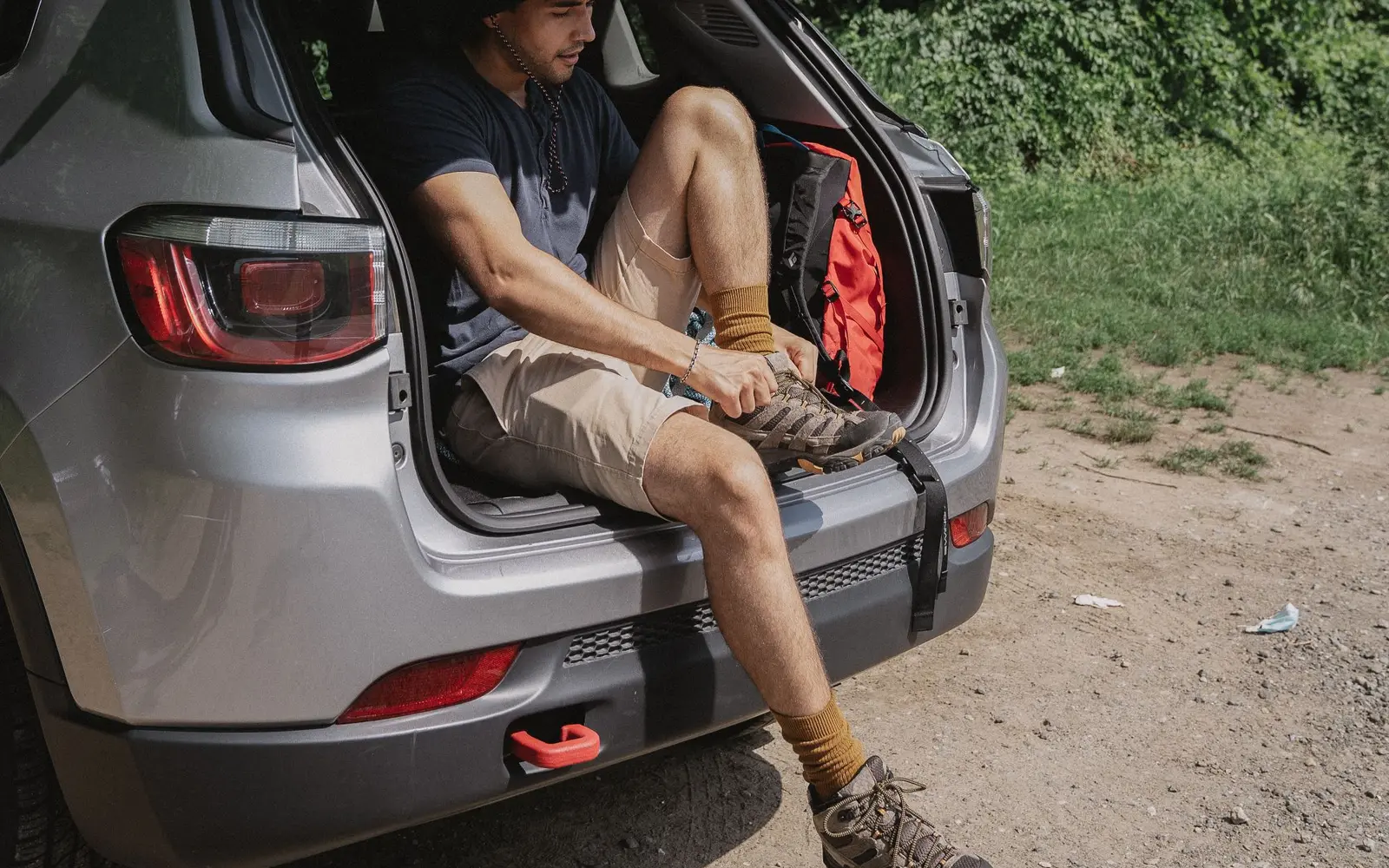 Camper sitting in the open trunk of an SUV lacing up hiking boots