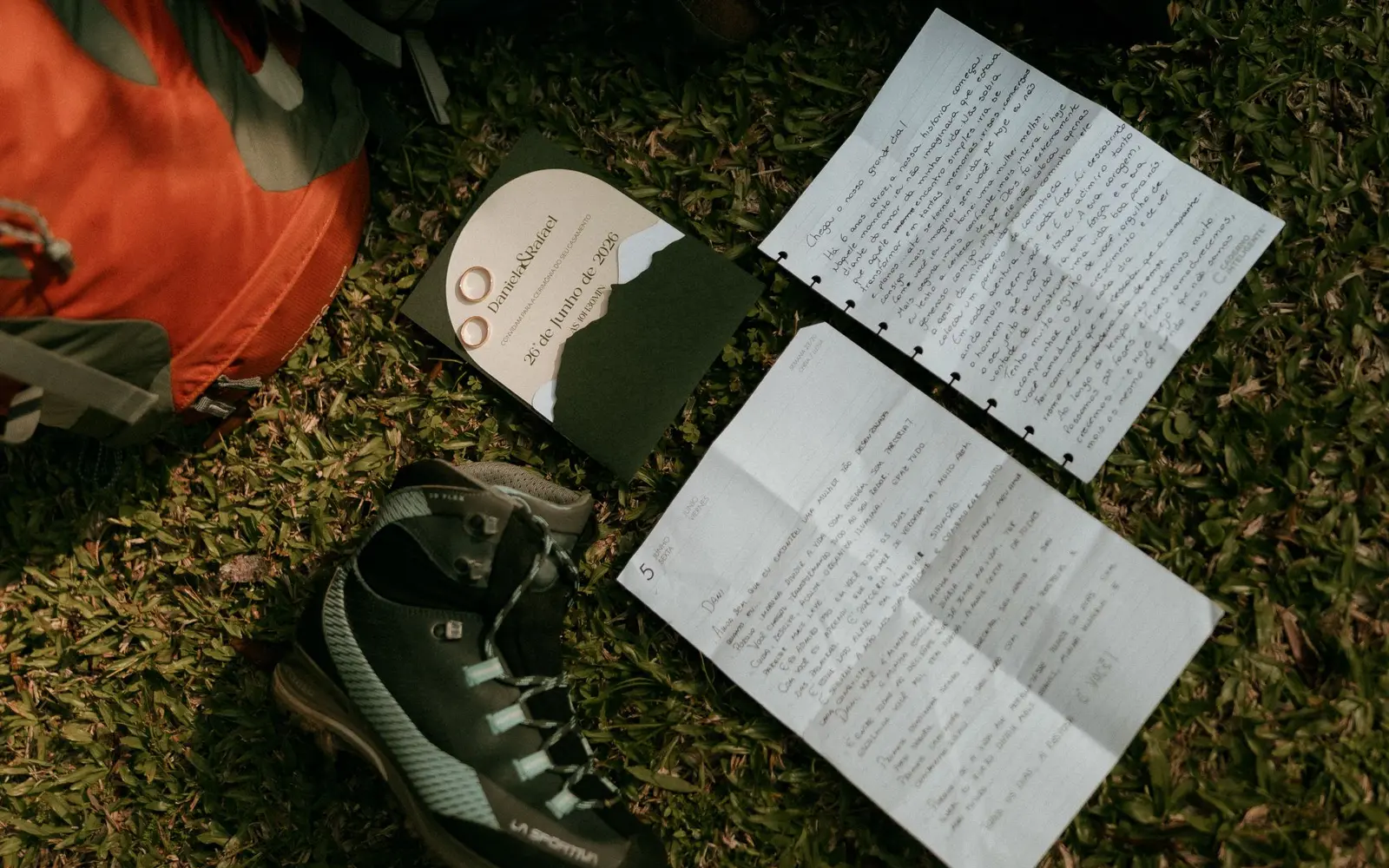 Hiking boots, backpacks and handwritten trip notes laid out on grass before a weekend trip